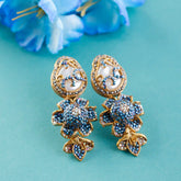 Gold and blue floral earrings on a teal background