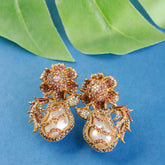 Gold floral earrings with pearls on a blue background with green leaves