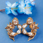 Gold and pearl earrings on a blue background with blue flowers.