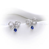 Bow-shaped earrings with blue teardrop stones on a white background