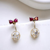 Pair of earrings with red gemstones and clear crystal elements on a white background