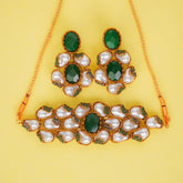 Ornate necklace and earrings set with green and pearl-like stones on a yellow background