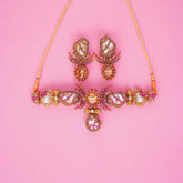 Ornate necklace and earrings on a pink background