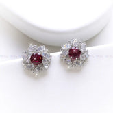 Pair of earrings with red gemstones and diamond-like accents on a white background