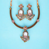 Ornate necklace and earrings set on a light blue background