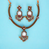 Ornate necklace and earrings set on a light blue background