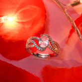 Silver ring with a pink gemstone on a red rose background
