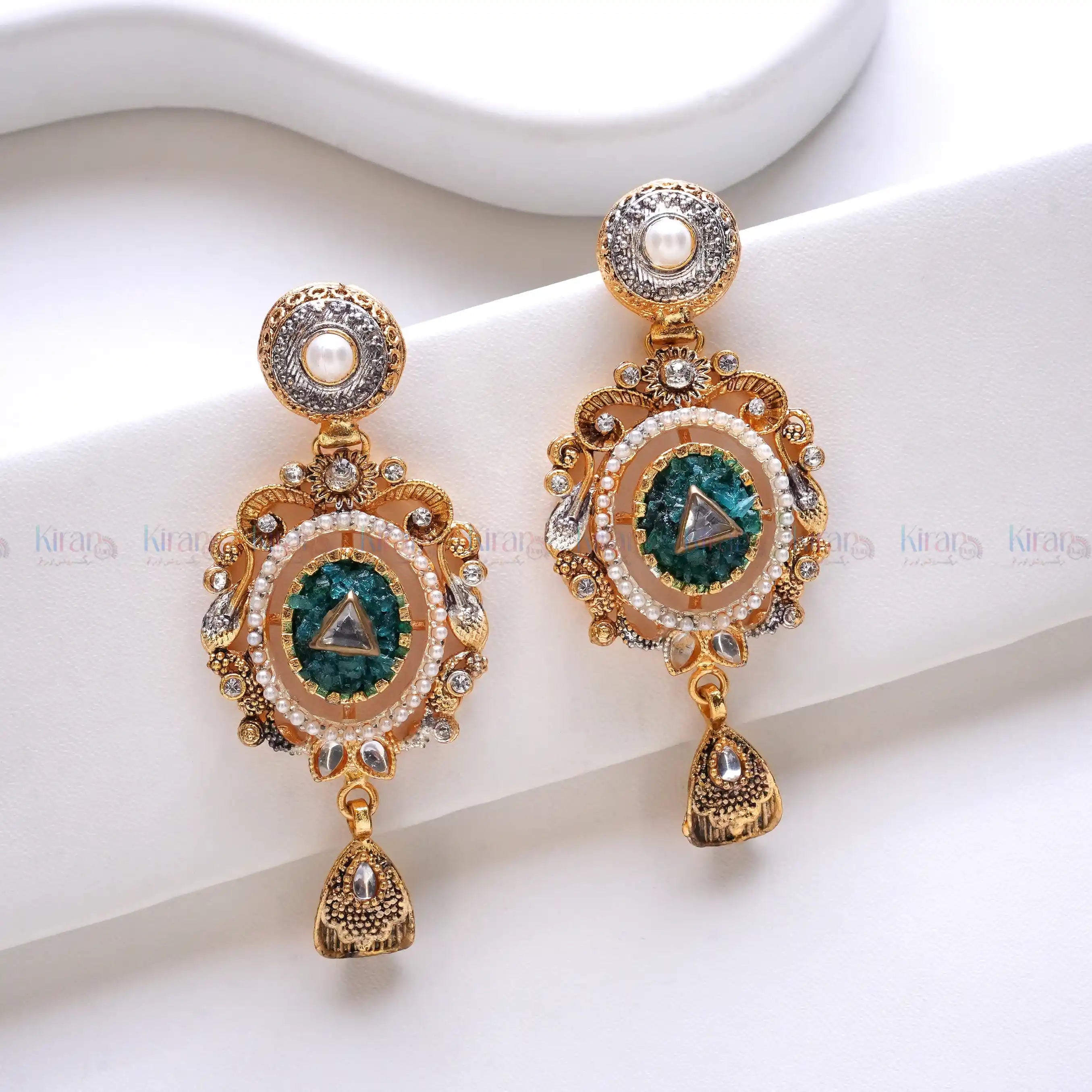 Ornate gold earrings with green gemstones on a white background