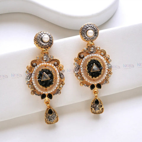Ornate gold earrings with black stones and pearls on a white background