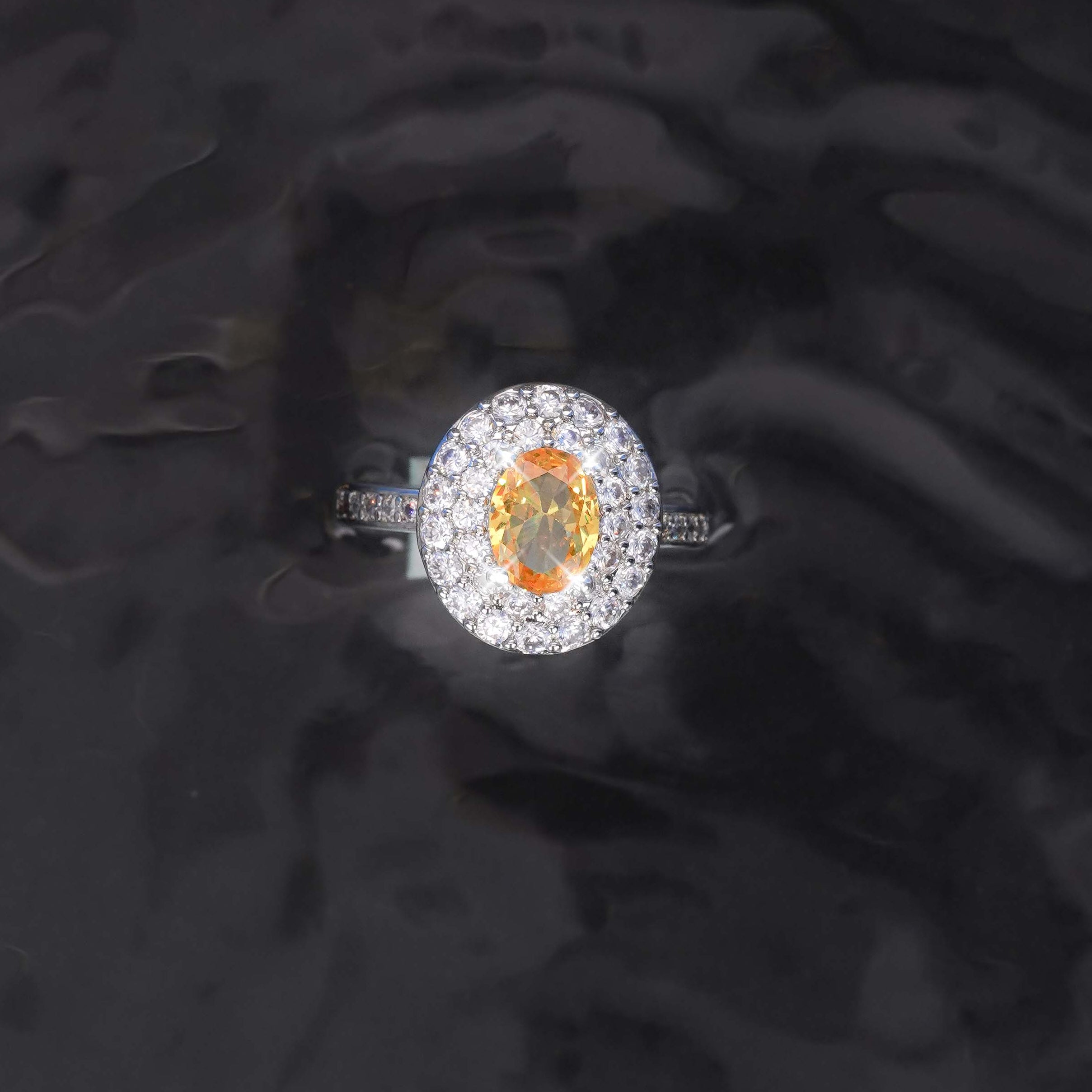 Diamond ring with a central orange gemstone on a dark textured background