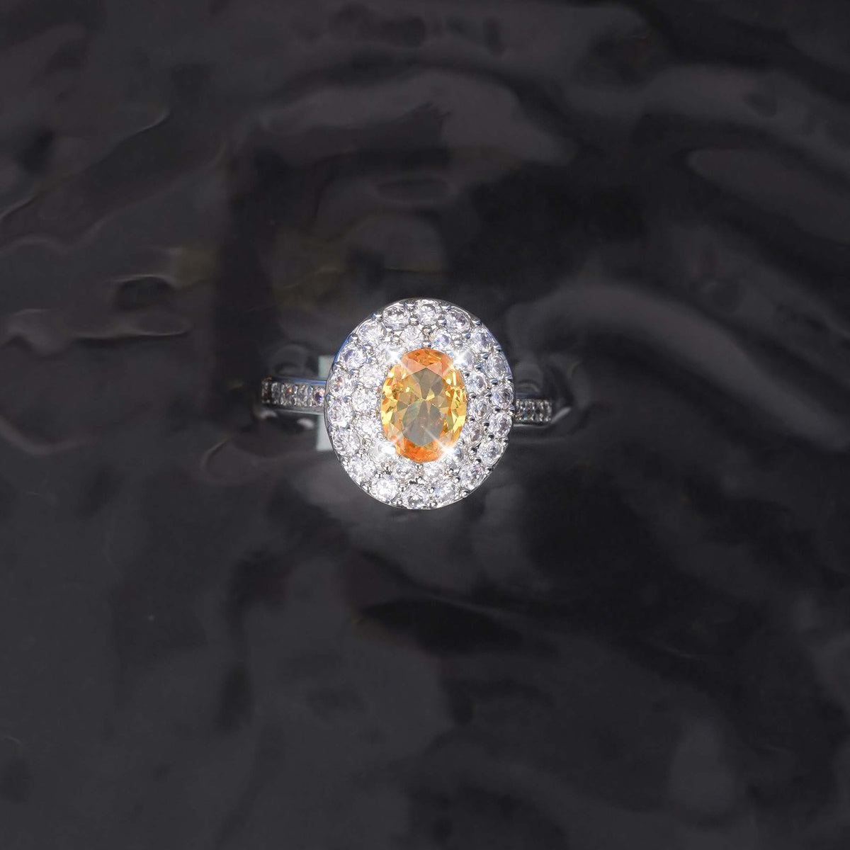 Diamond ring with a central orange gemstone on a dark textured background