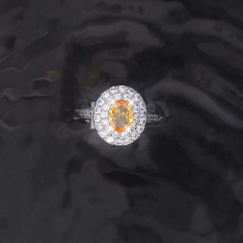 Diamond ring with a central orange gemstone on a dark textured background