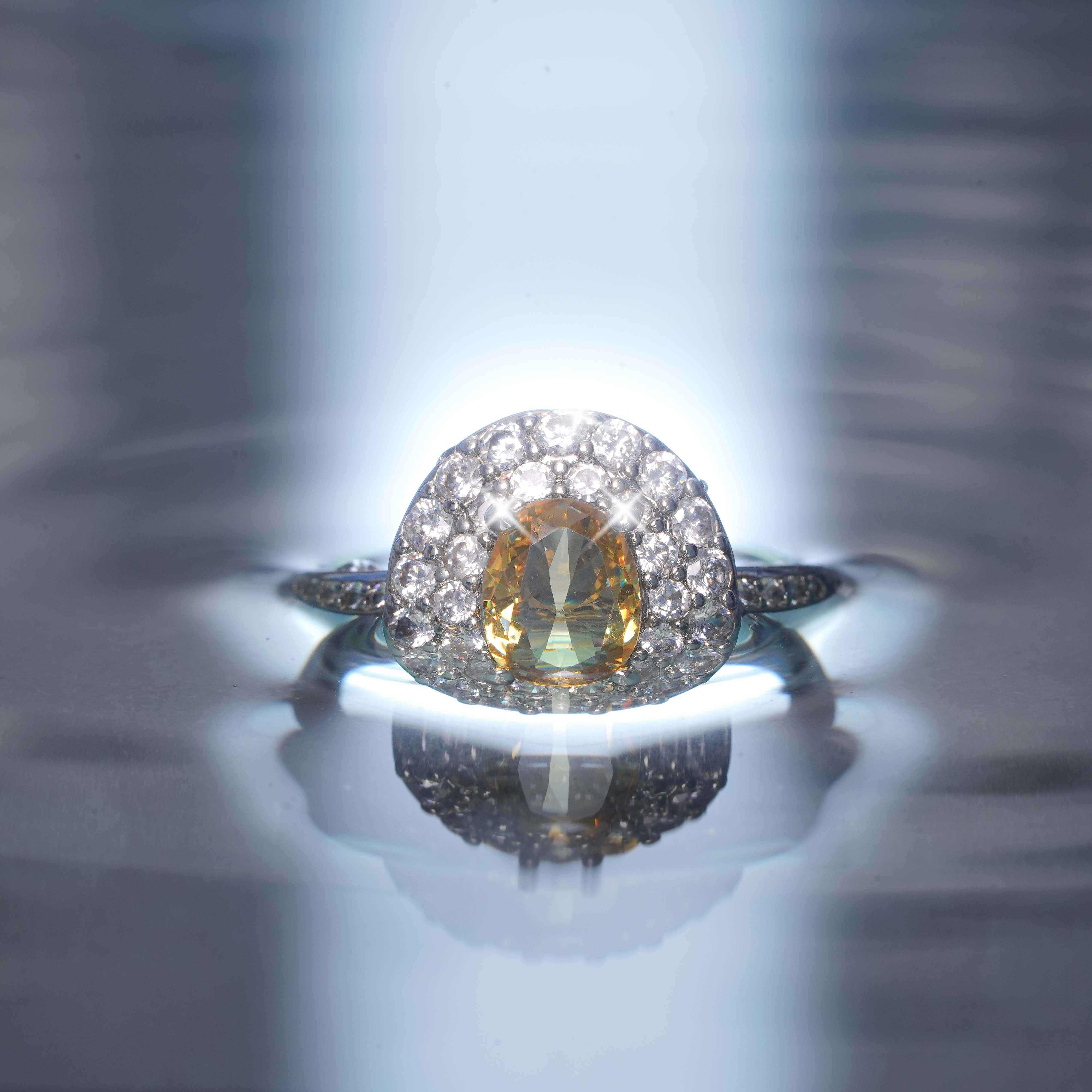 Ring with a large central gemstone and smaller stones on a reflective surface