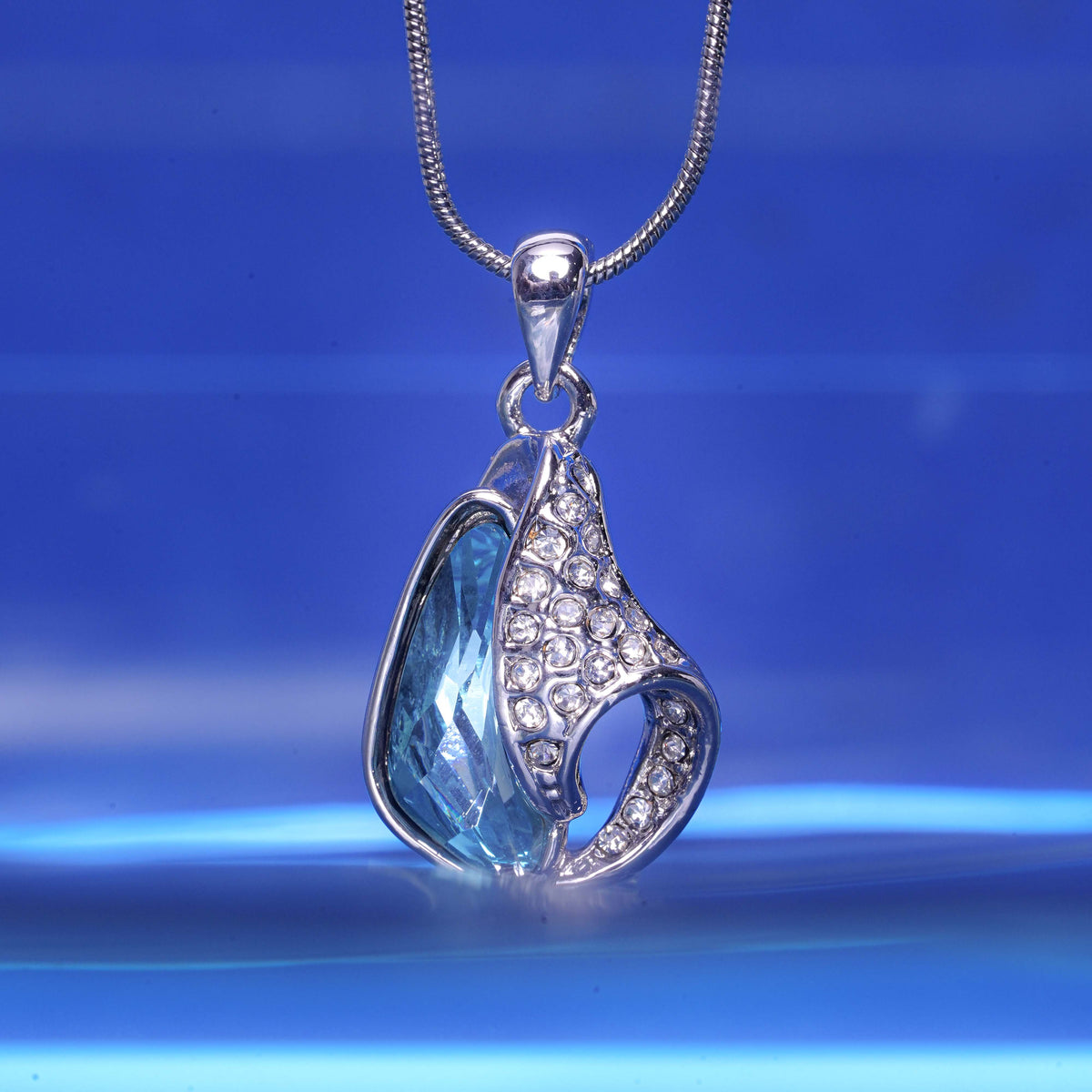 Silver pendant with blue stone on a blue background
