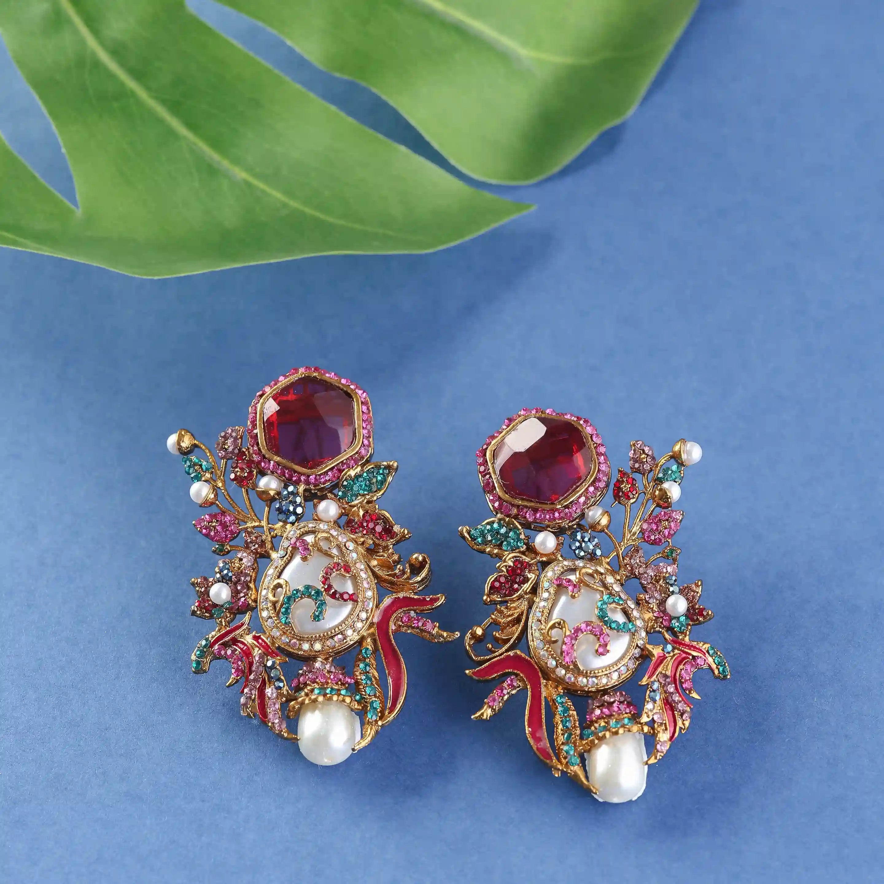 earrings with gemstones and pearls on a blue background