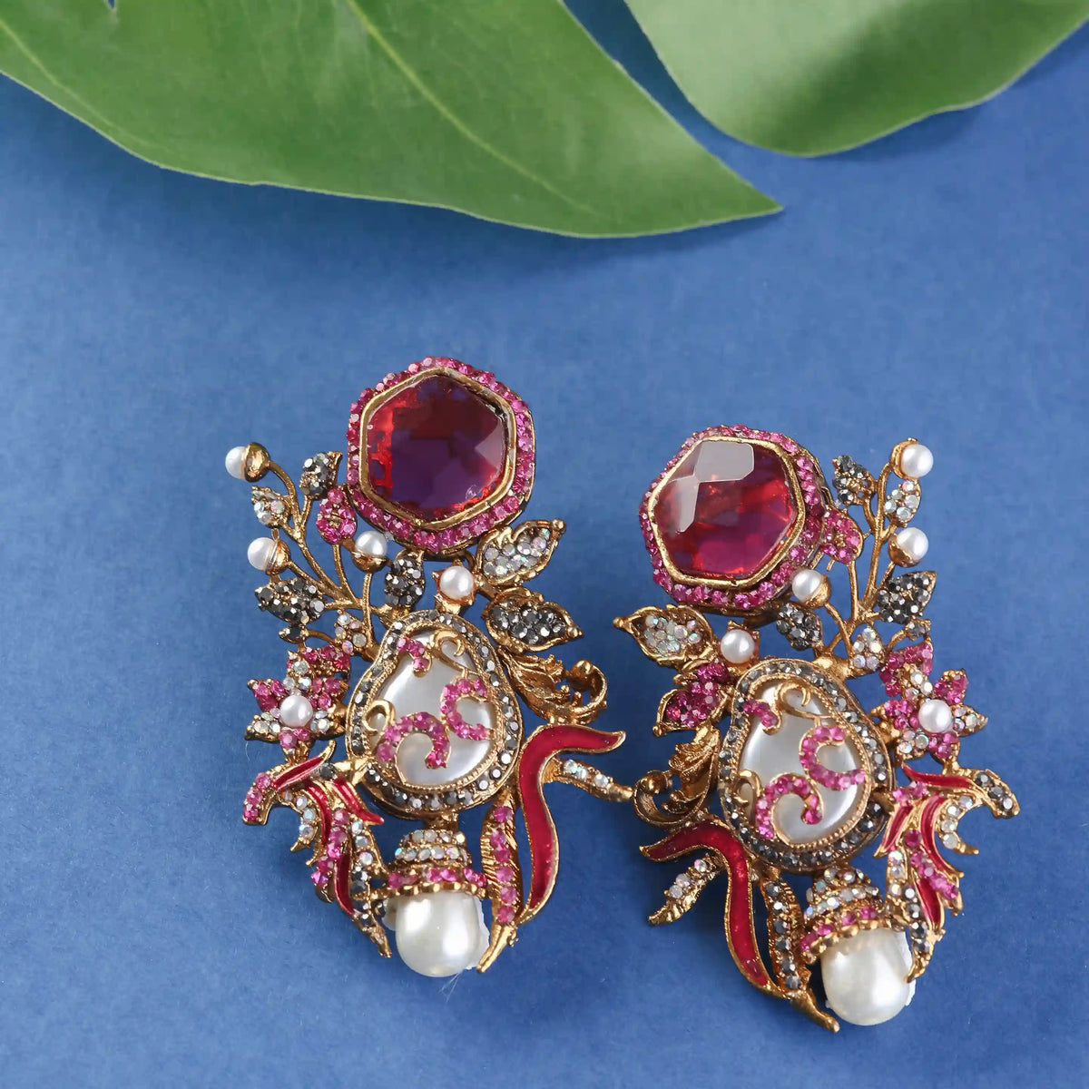 Ornate earrings with red gemstones, pearls, and gold accents