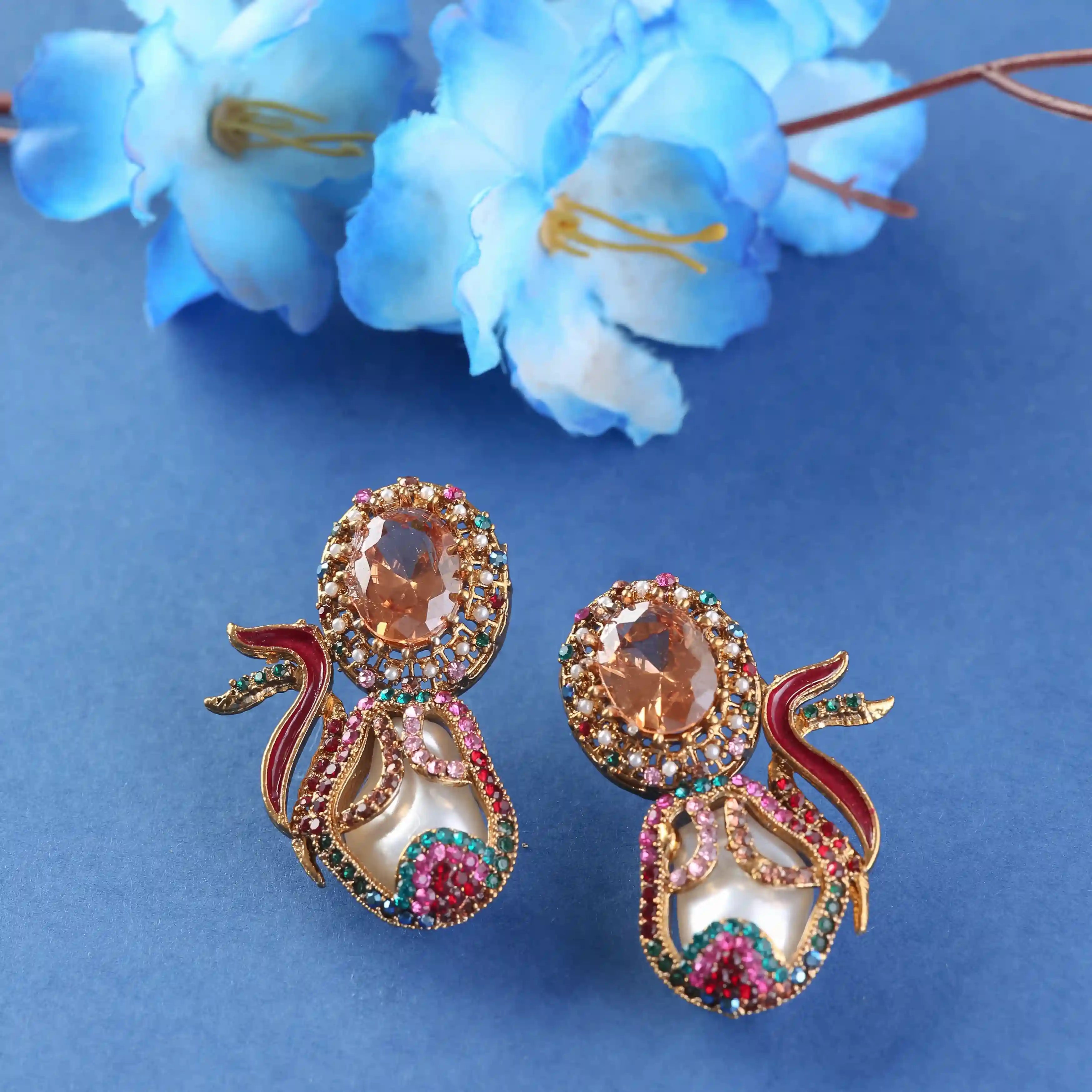 Ornate earrings with gemstones on a blue background with flowers