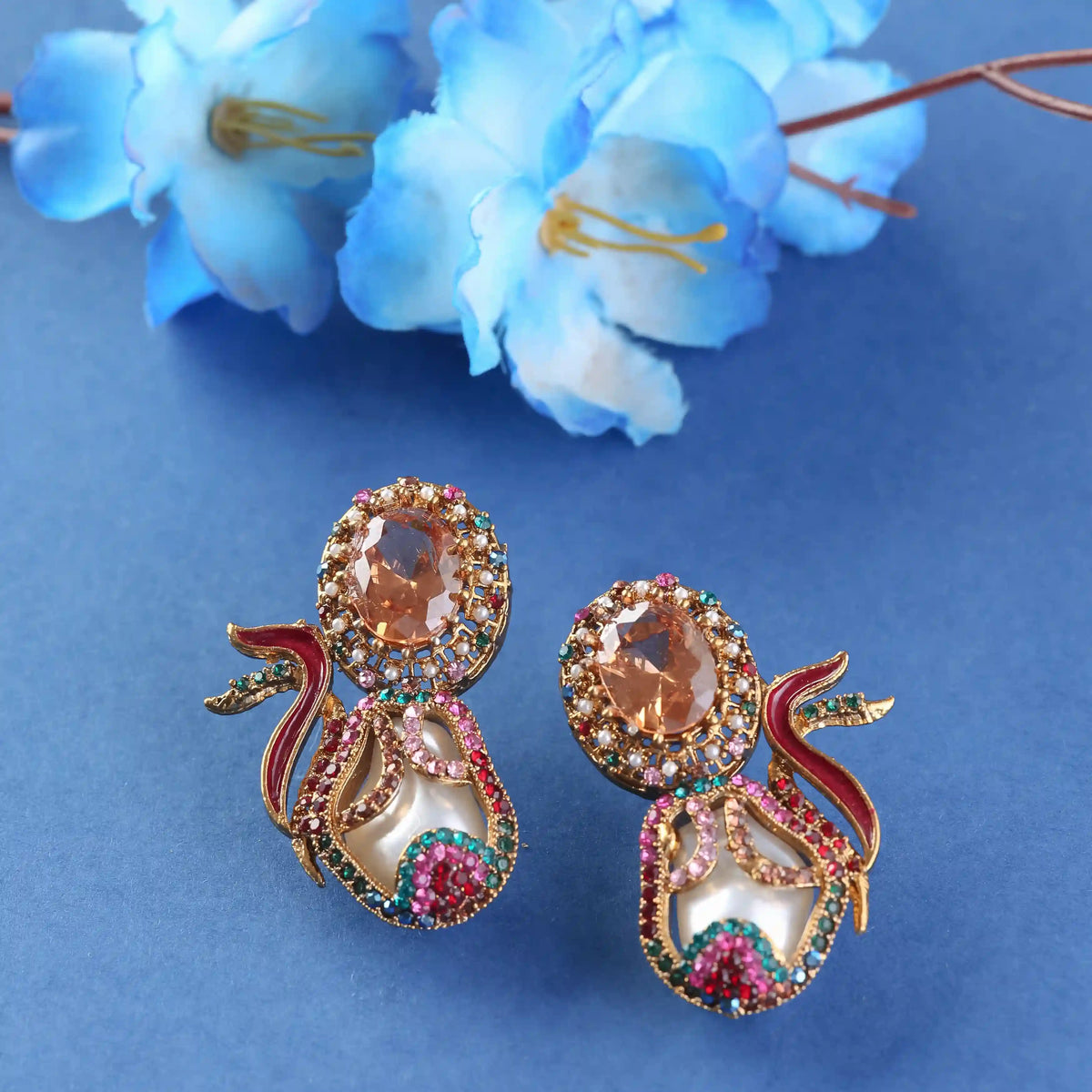 Ornate earrings with gemstones on a blue background with flowers