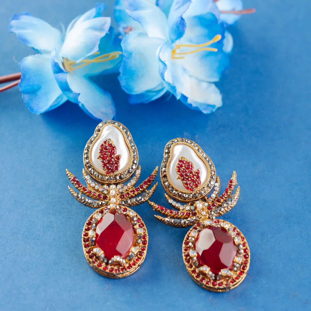 Ornate earrings with red and gold details on a blue background