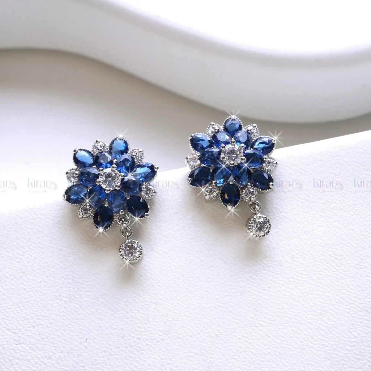 Pair of blue flower-shaped earrings on a white surface