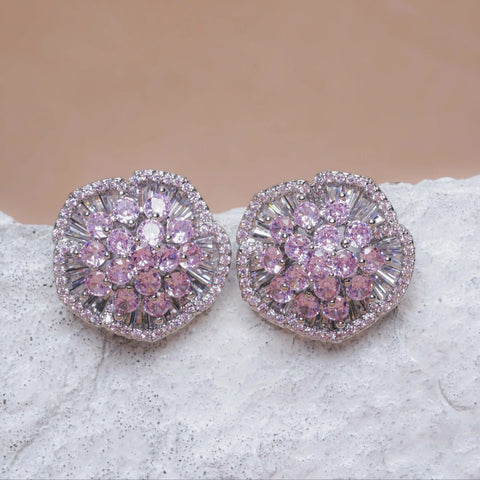 Pair of pink gemstone earrings on a textured surface with a beige background