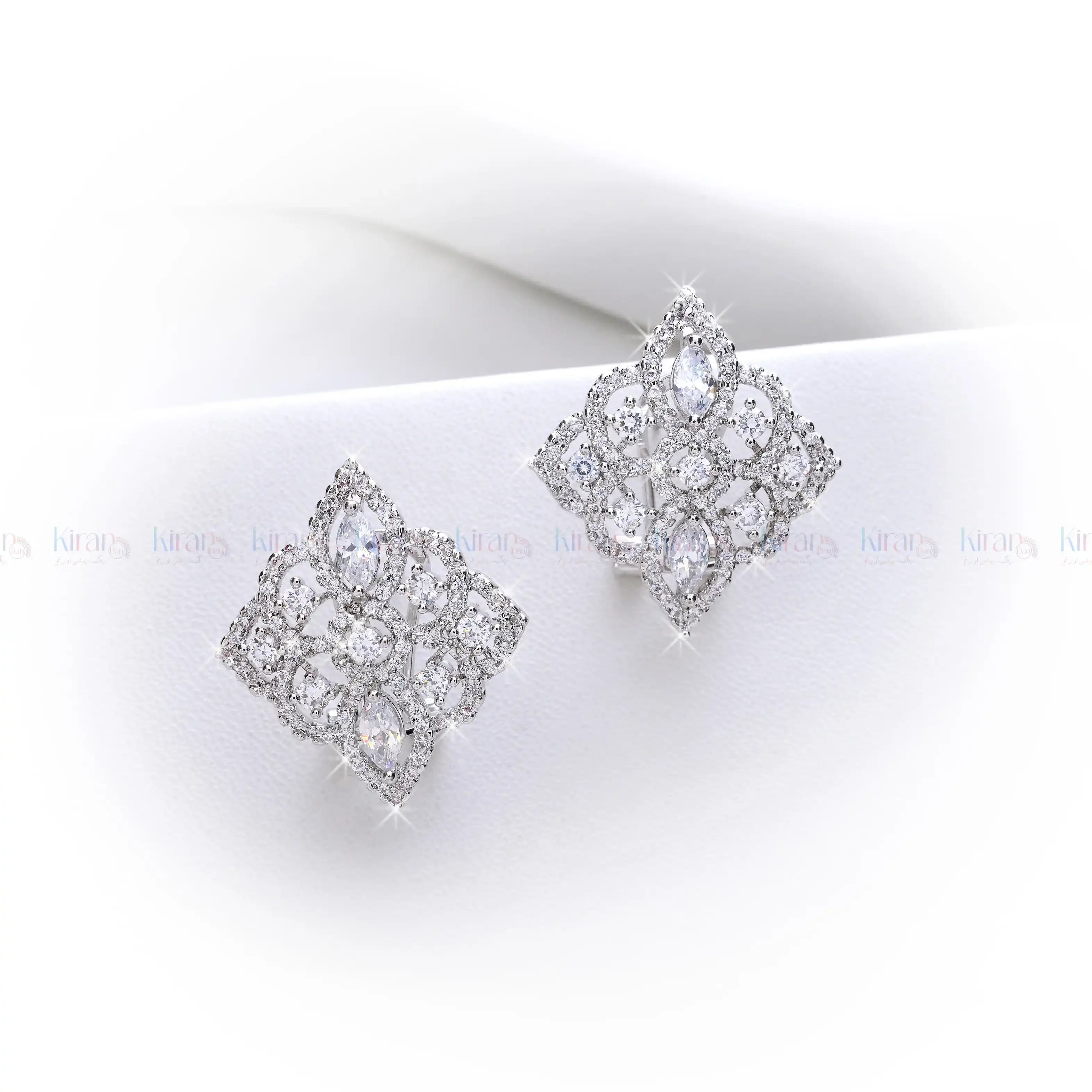 Pair of silver earrings with clear gemstones on a white surface