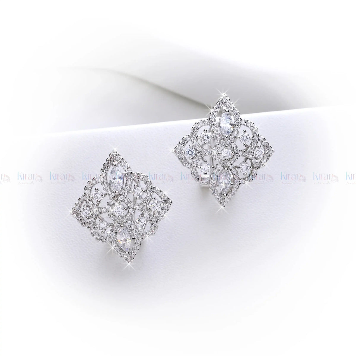 Pair of silver earrings with clear gemstones on a white surface