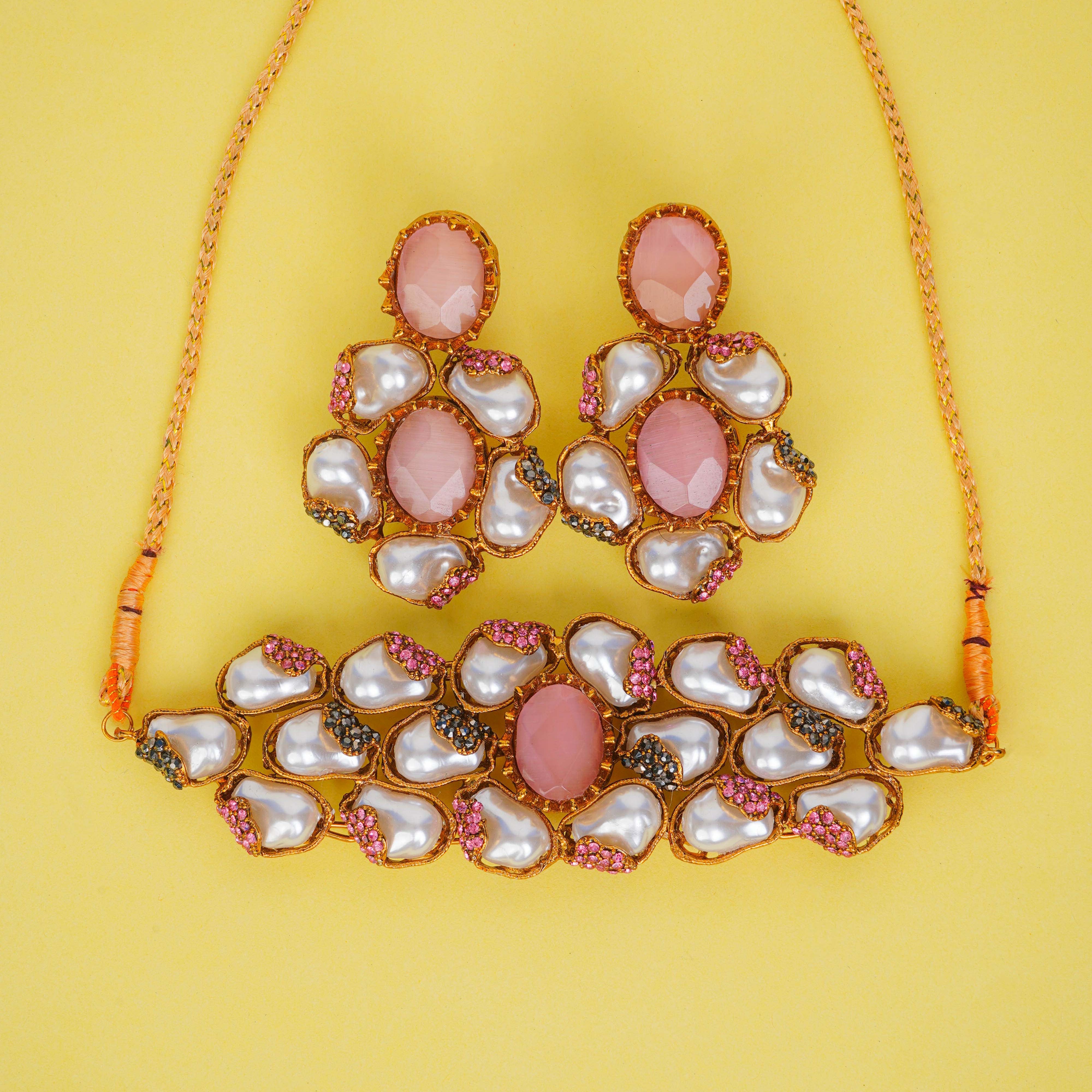 Necklace and earrings set with pink and white stones on a yellow background