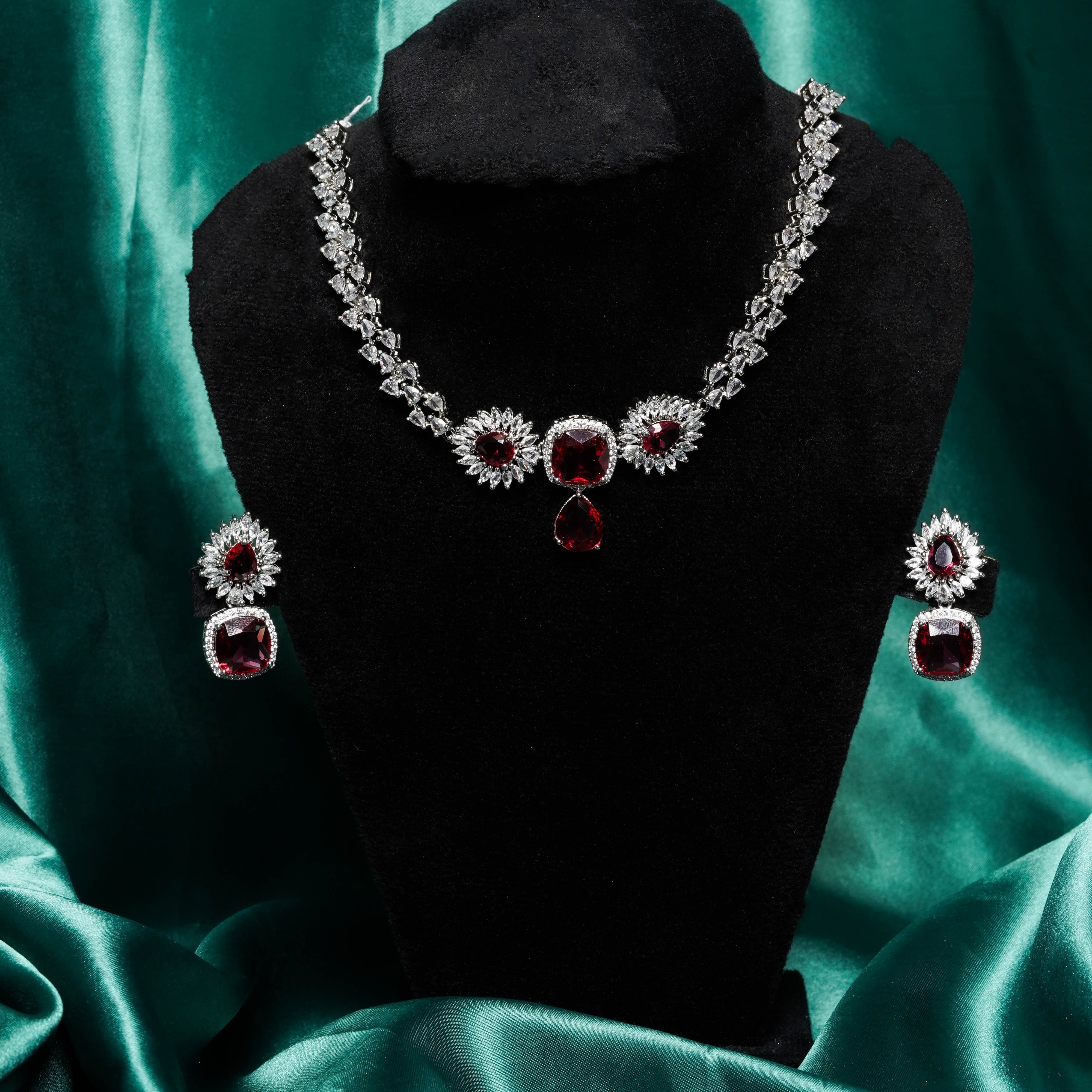 Jewelry set with necklace and earrings on a black mannequin against a teal fabric background
