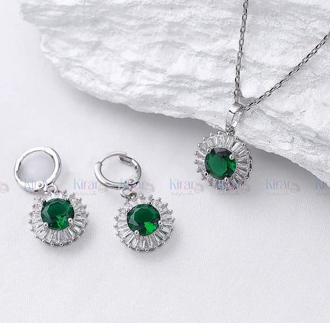 Silver jewelry set with green gemstones on a white background