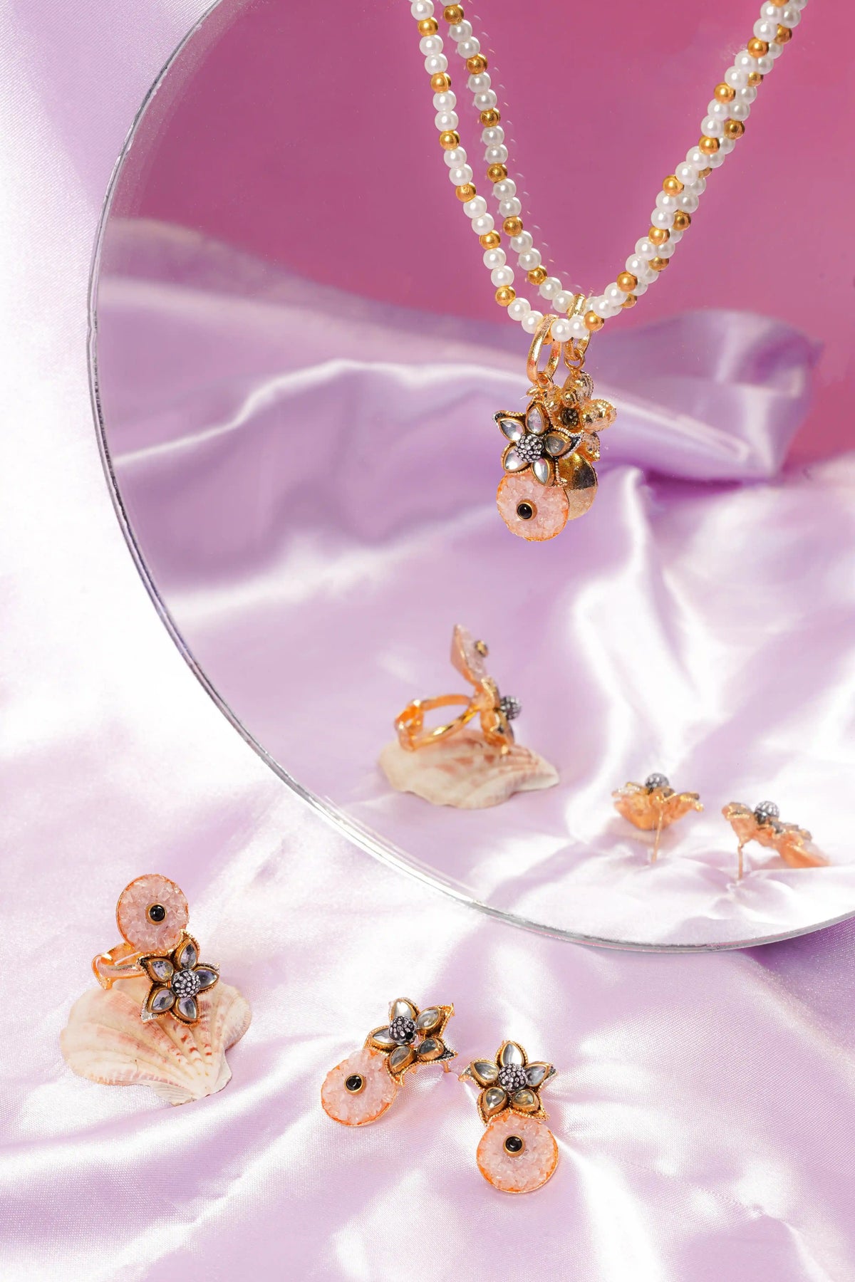 Set of pearl and gold jewelry on a pink fabric background