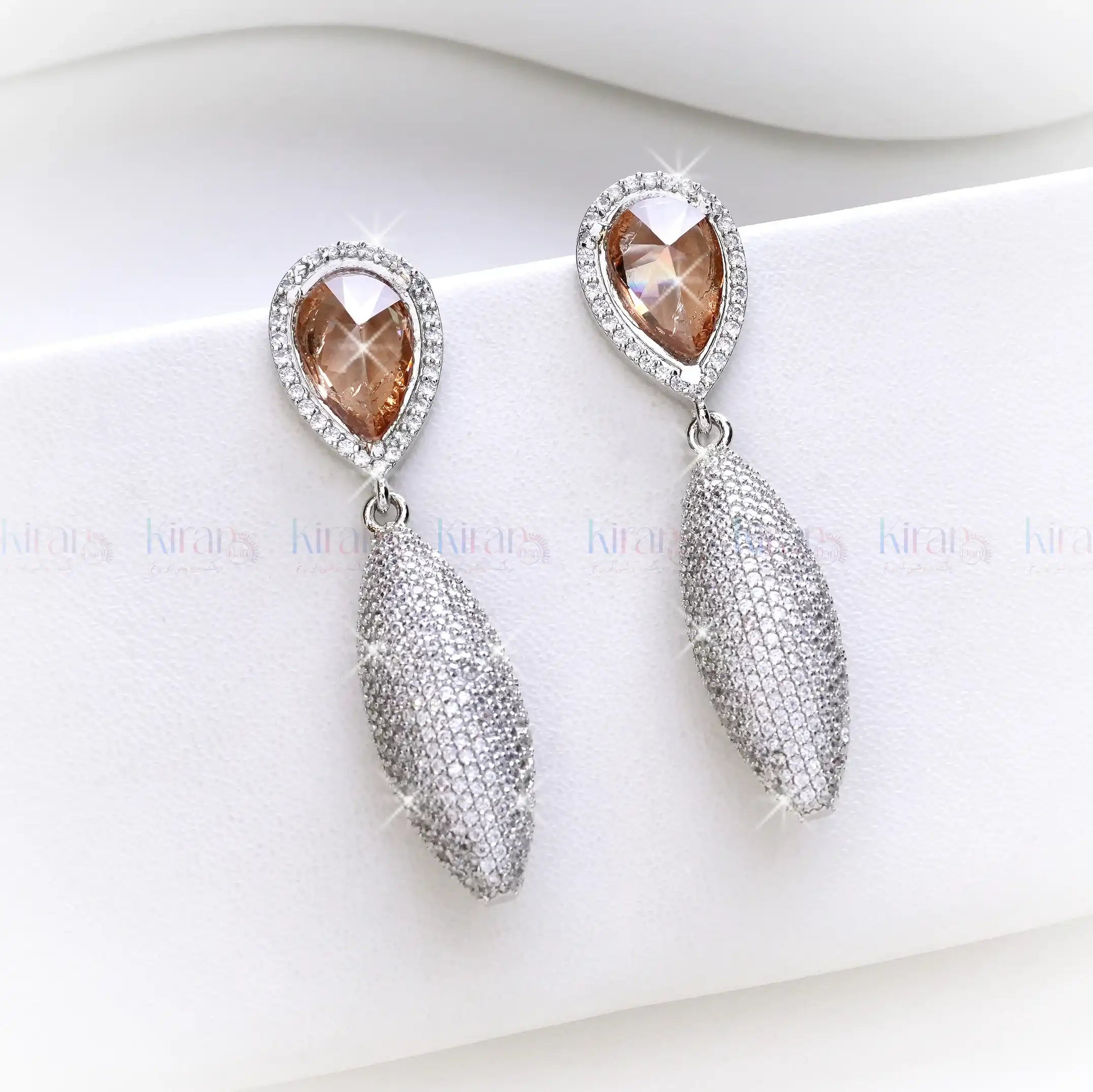 Pair of earrings with teardrop-shaped brown gemstones and silver accents on a white background.