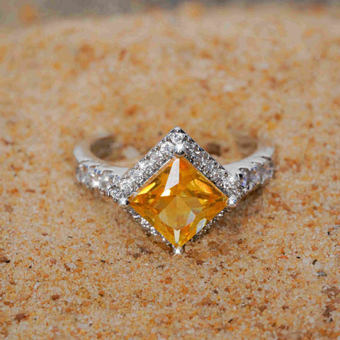 Silver ring with a yellow gemstone on a sandy background