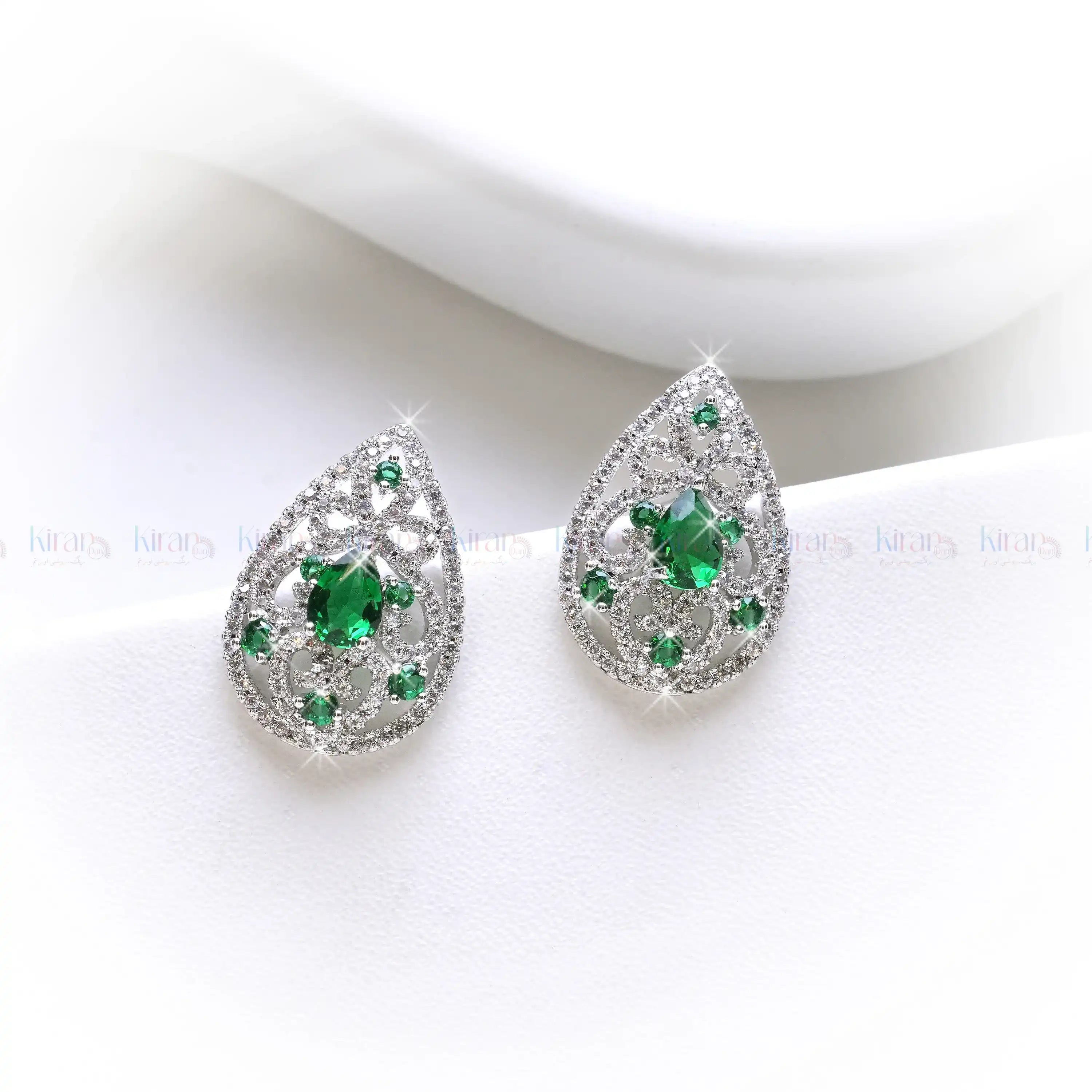 Teardrop-shaped earrings with green gemstones on a white background