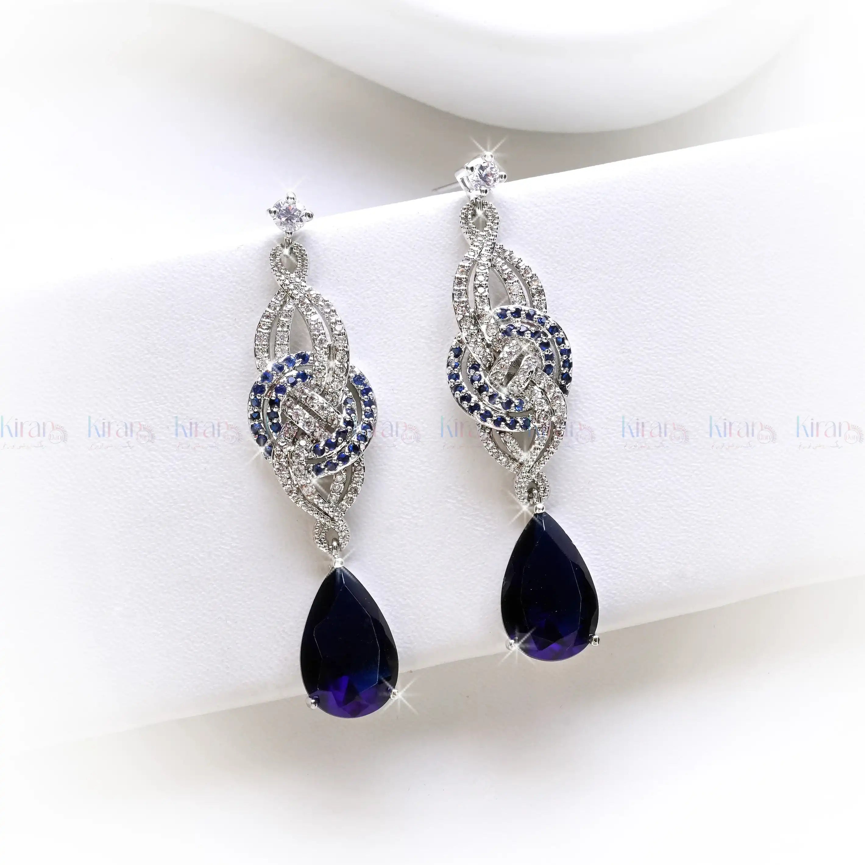 Pair of silver earrings with purple teardrop-shaped gemstones on a white background