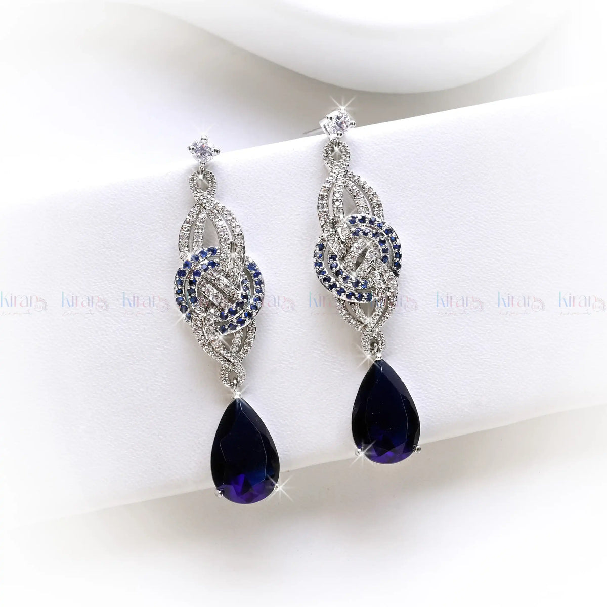Pair of silver earrings with purple teardrop-shaped gemstones on a white background