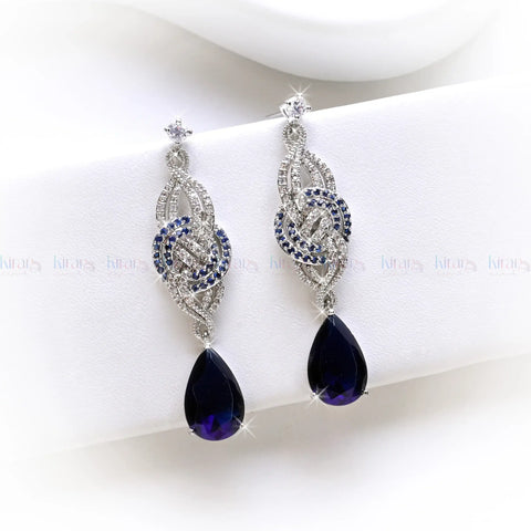 Pair of silver earrings with purple teardrop-shaped gemstones on a white background