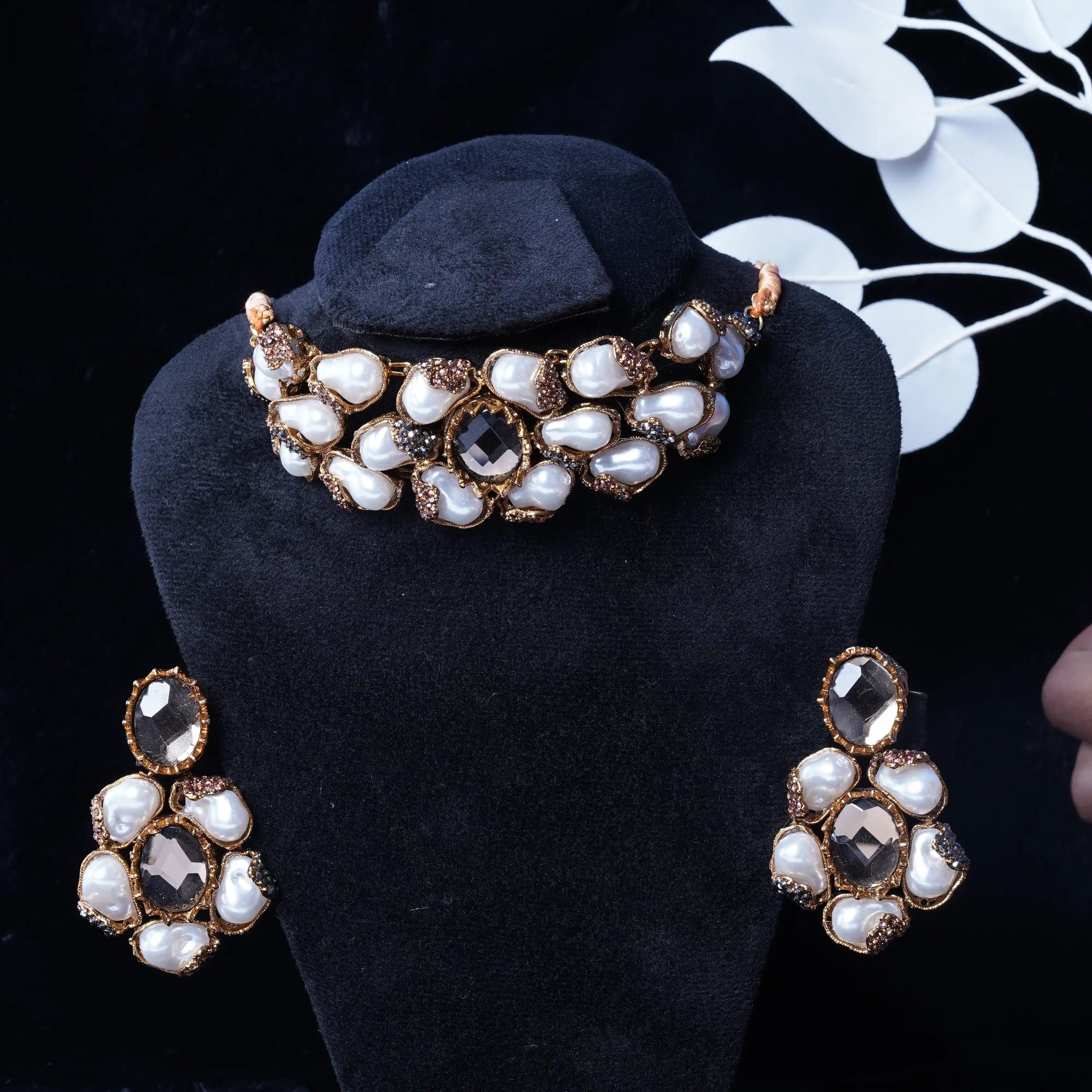 Jewelry set with necklace and earrings on a black stand against a dark background