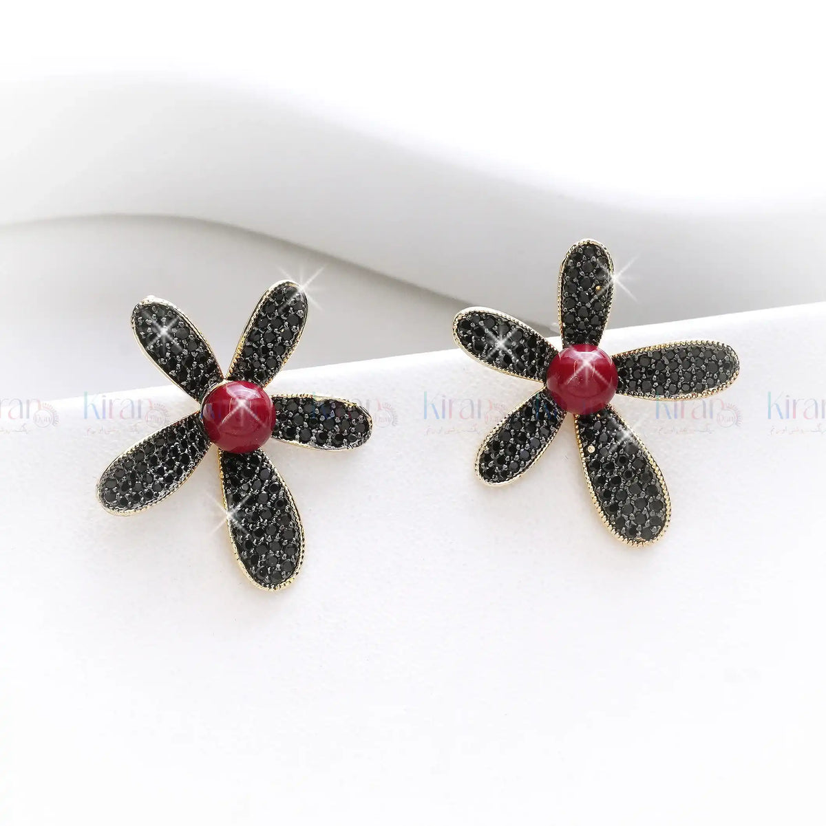 Flower-shaped earrings with black petals and a red center