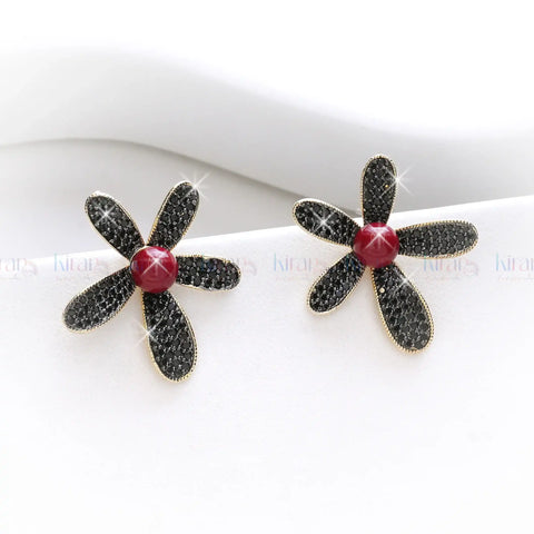 Flower-shaped earrings with black petals and a red center