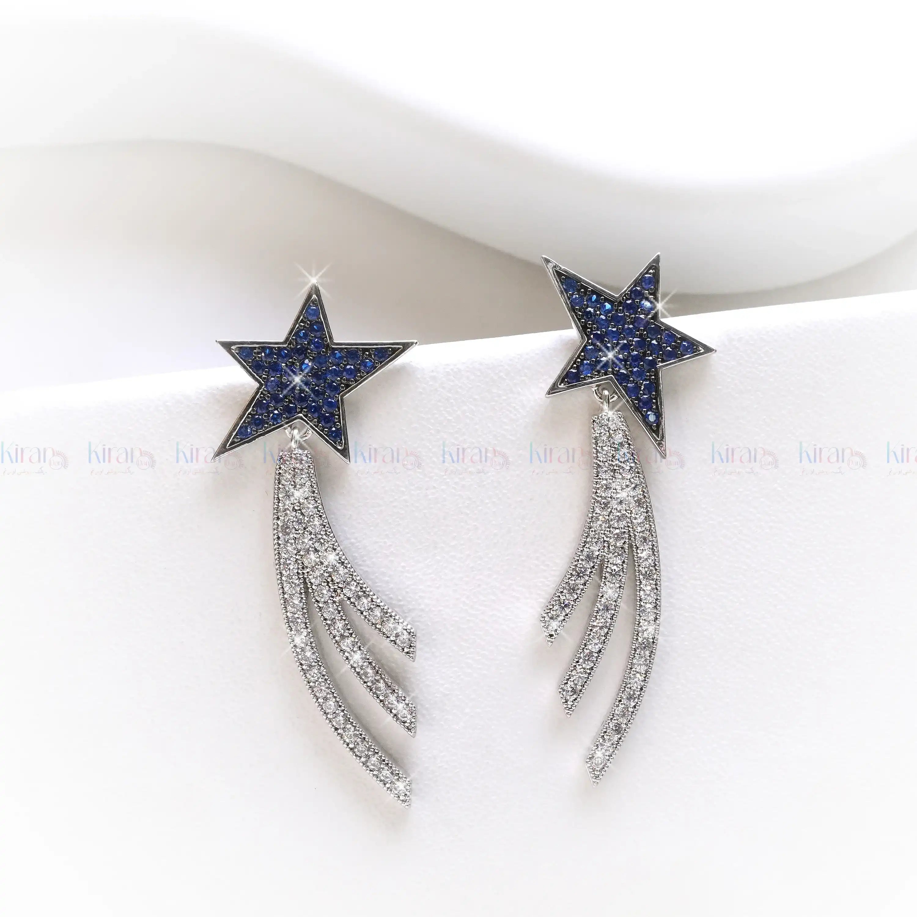 Star-shaped earrings with blue gemstones and silver accents on a white background
