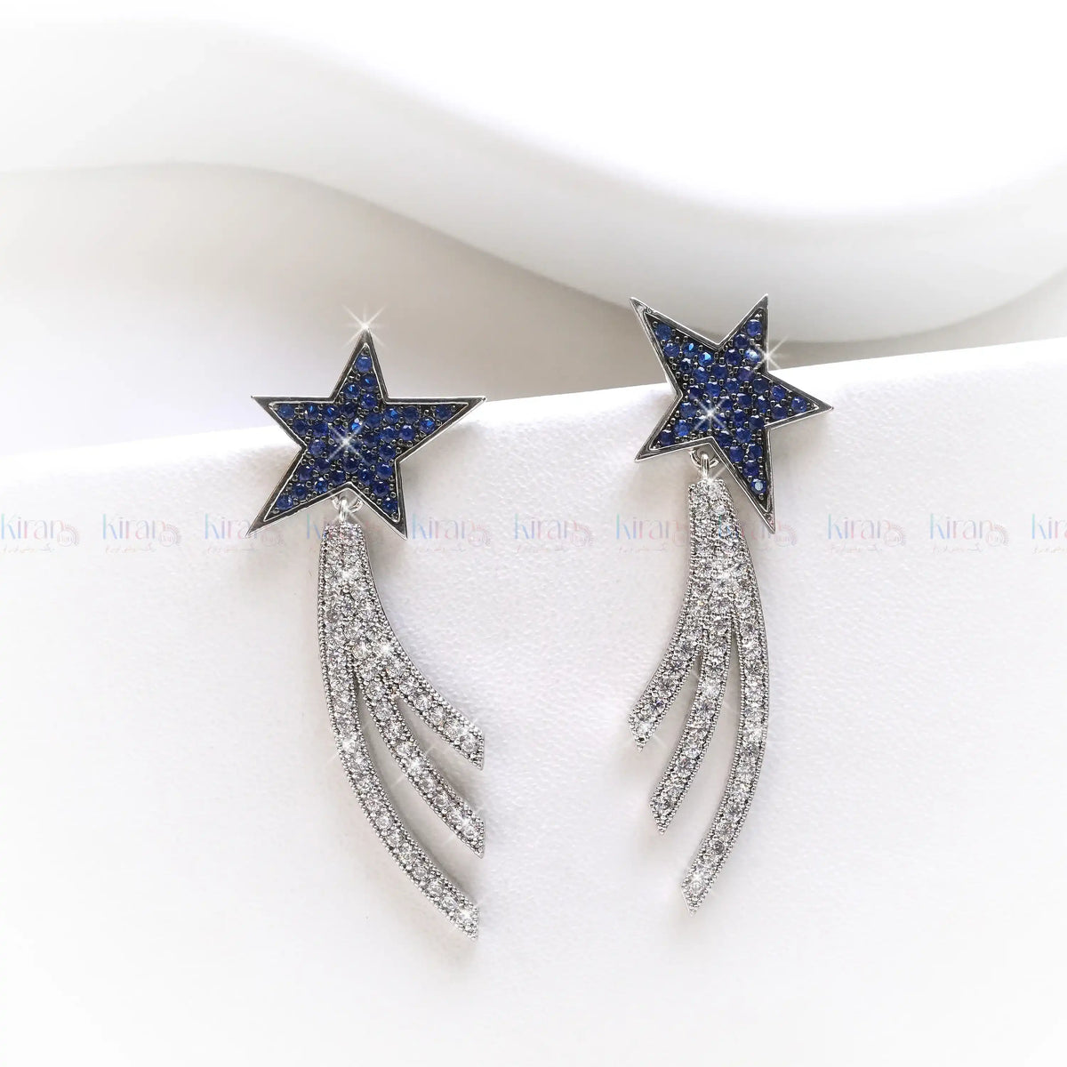 Star-shaped earrings with blue gemstones and silver accents on a white background