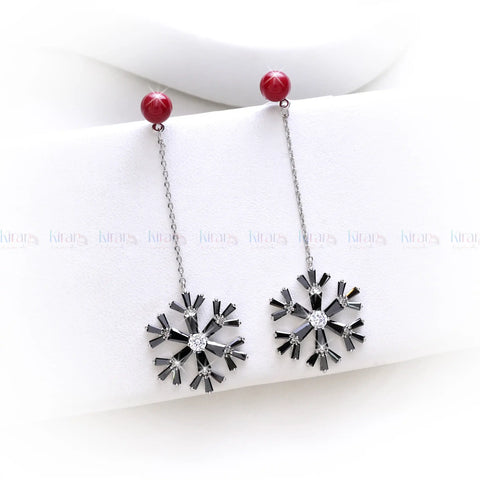 Pair of earrings with star-like design and red beads on a white background