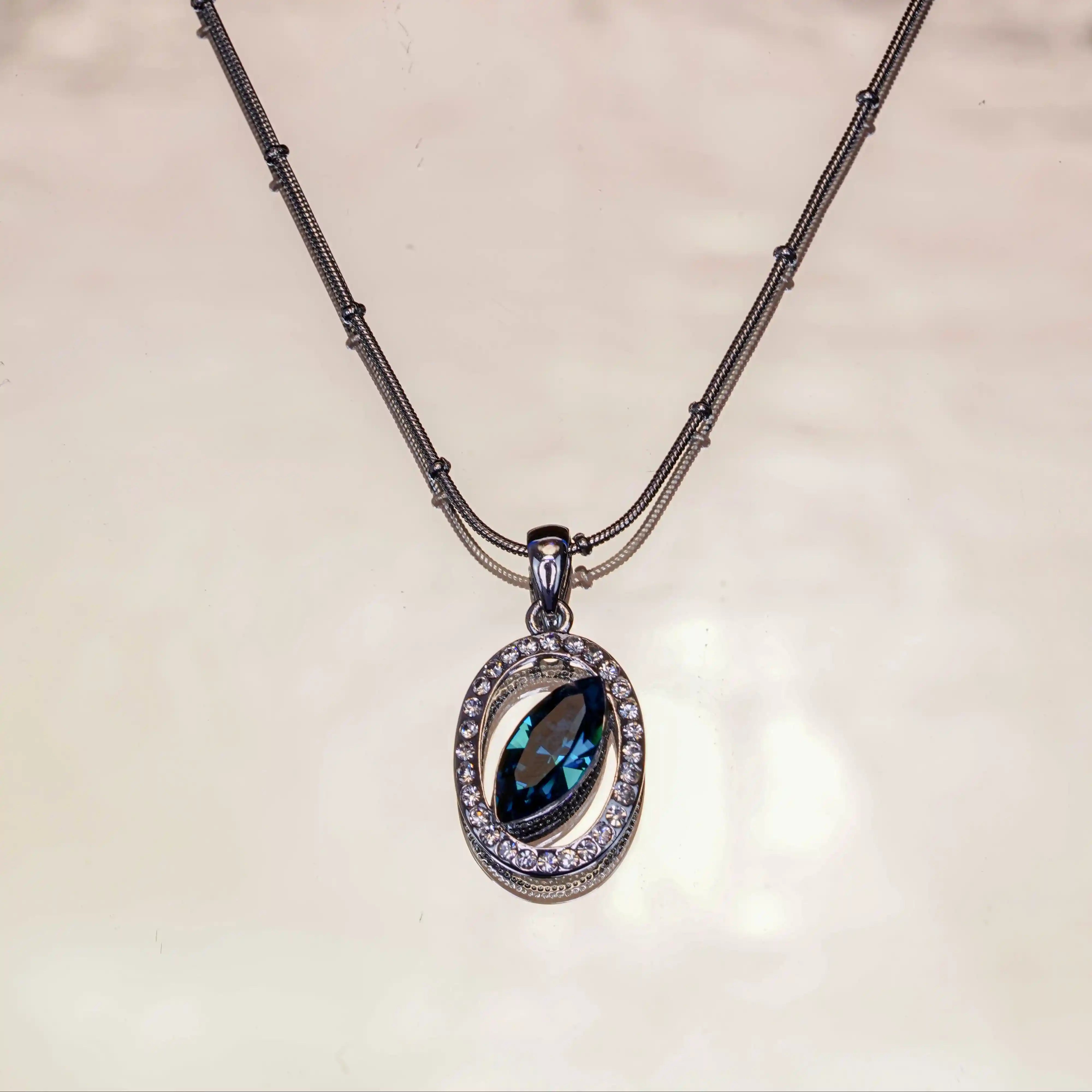 Necklace with a pendant featuring a blue gemstone on a beige background