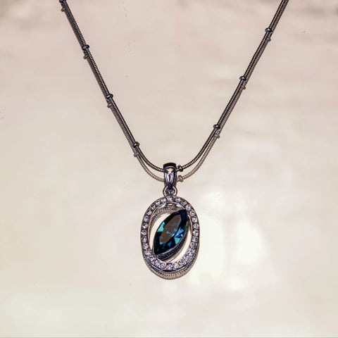 Necklace with a pendant featuring a blue gemstone on a beige background
