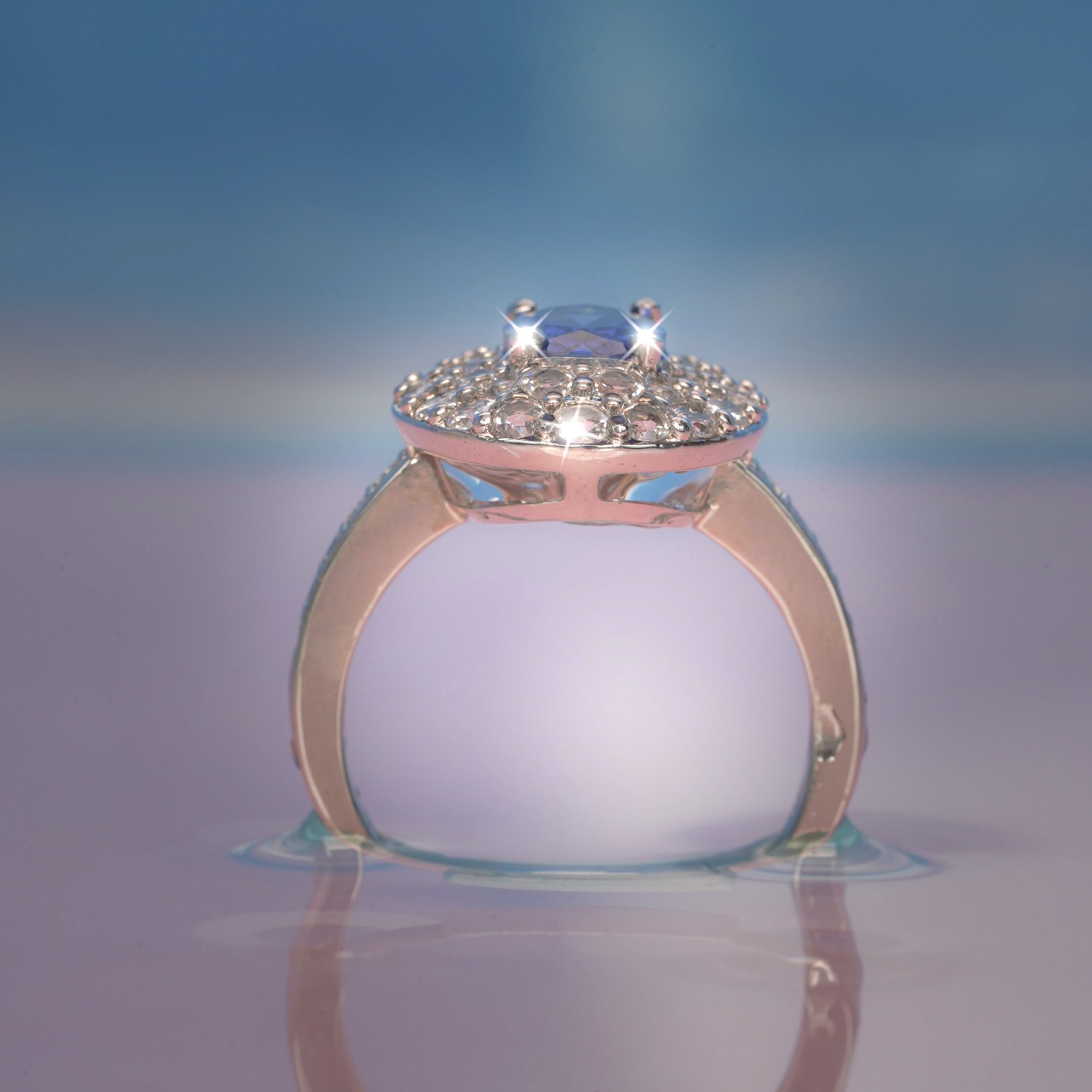 Rose gold ring with a diamond on a reflective surface