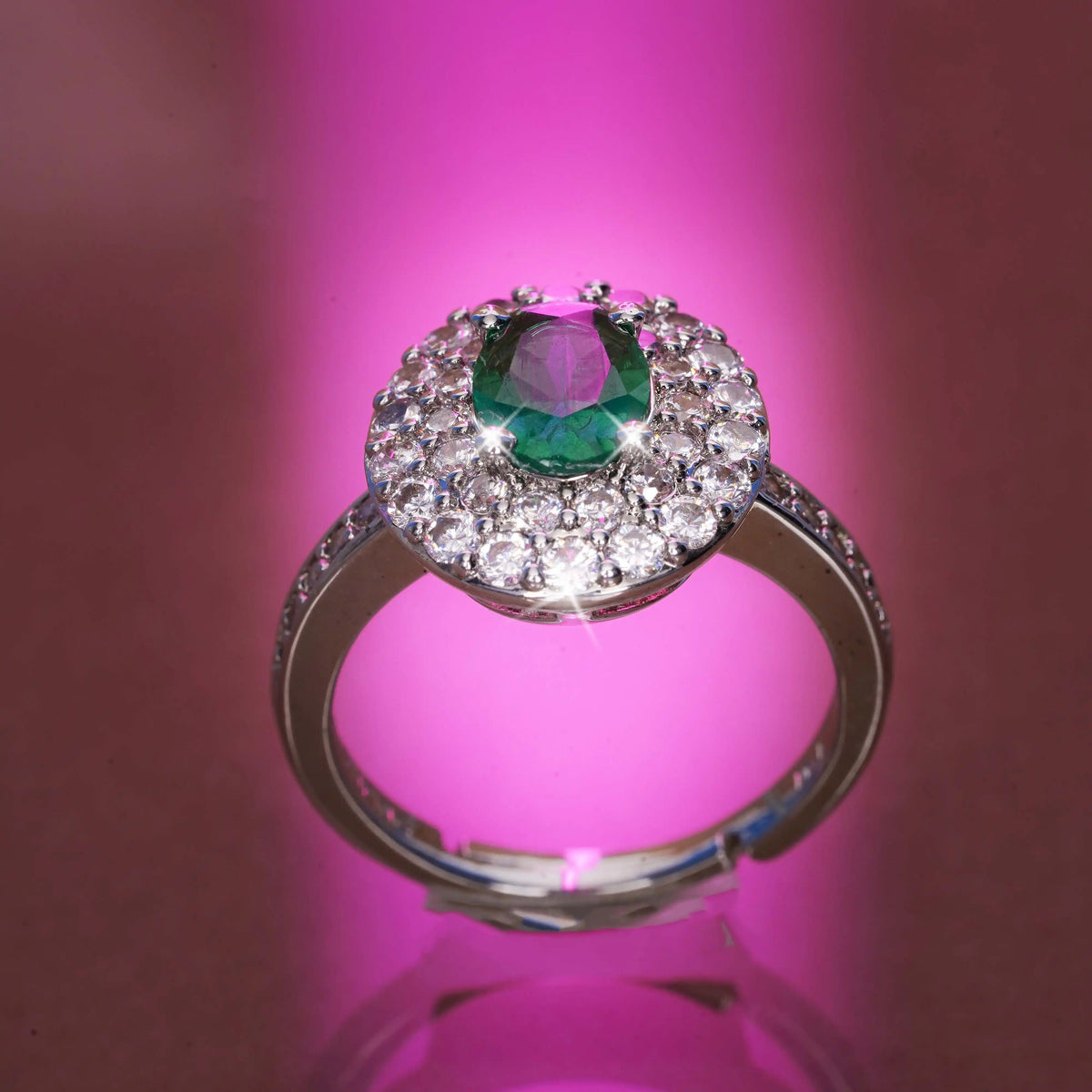 Ring with a green gemstone and diamond accents on a pink background