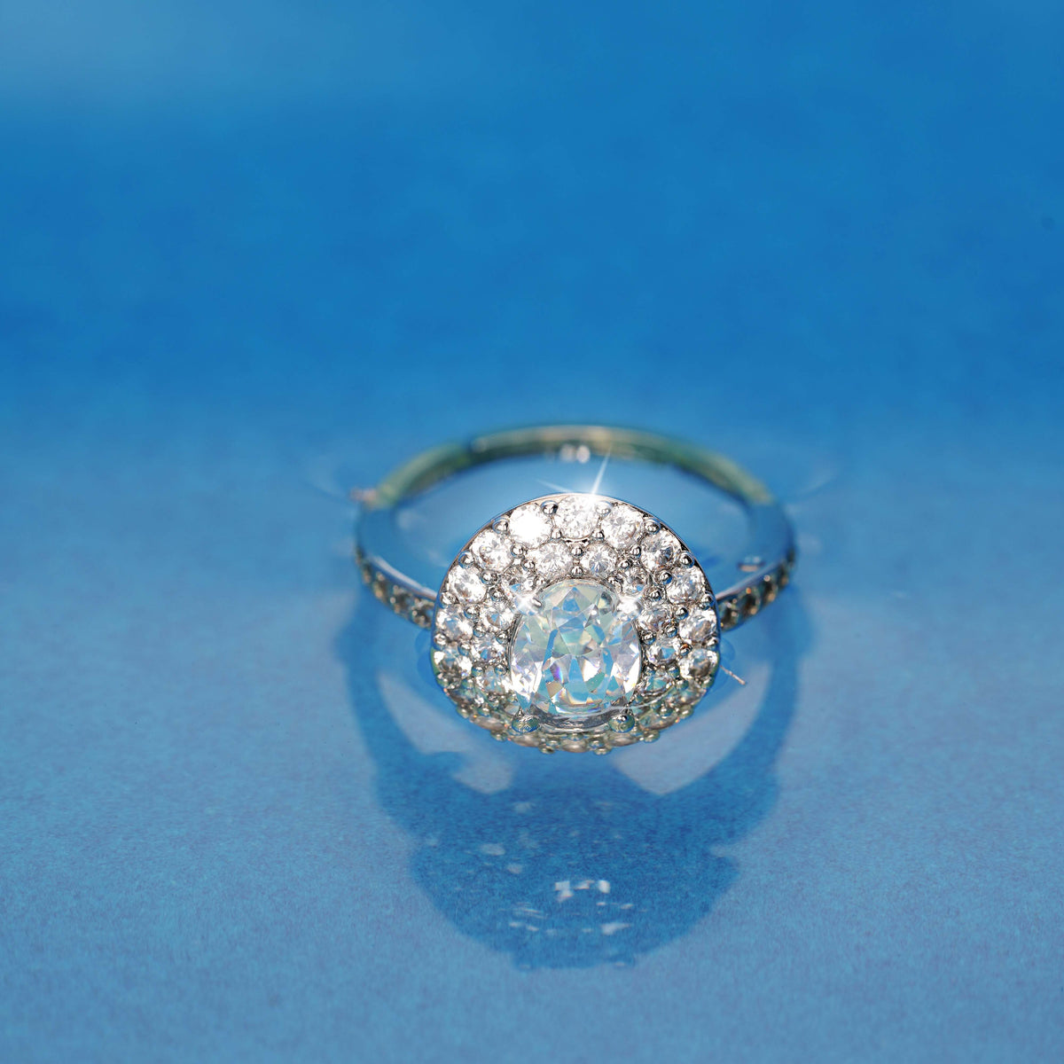 Silver ring with a large central gemstone on a blue background