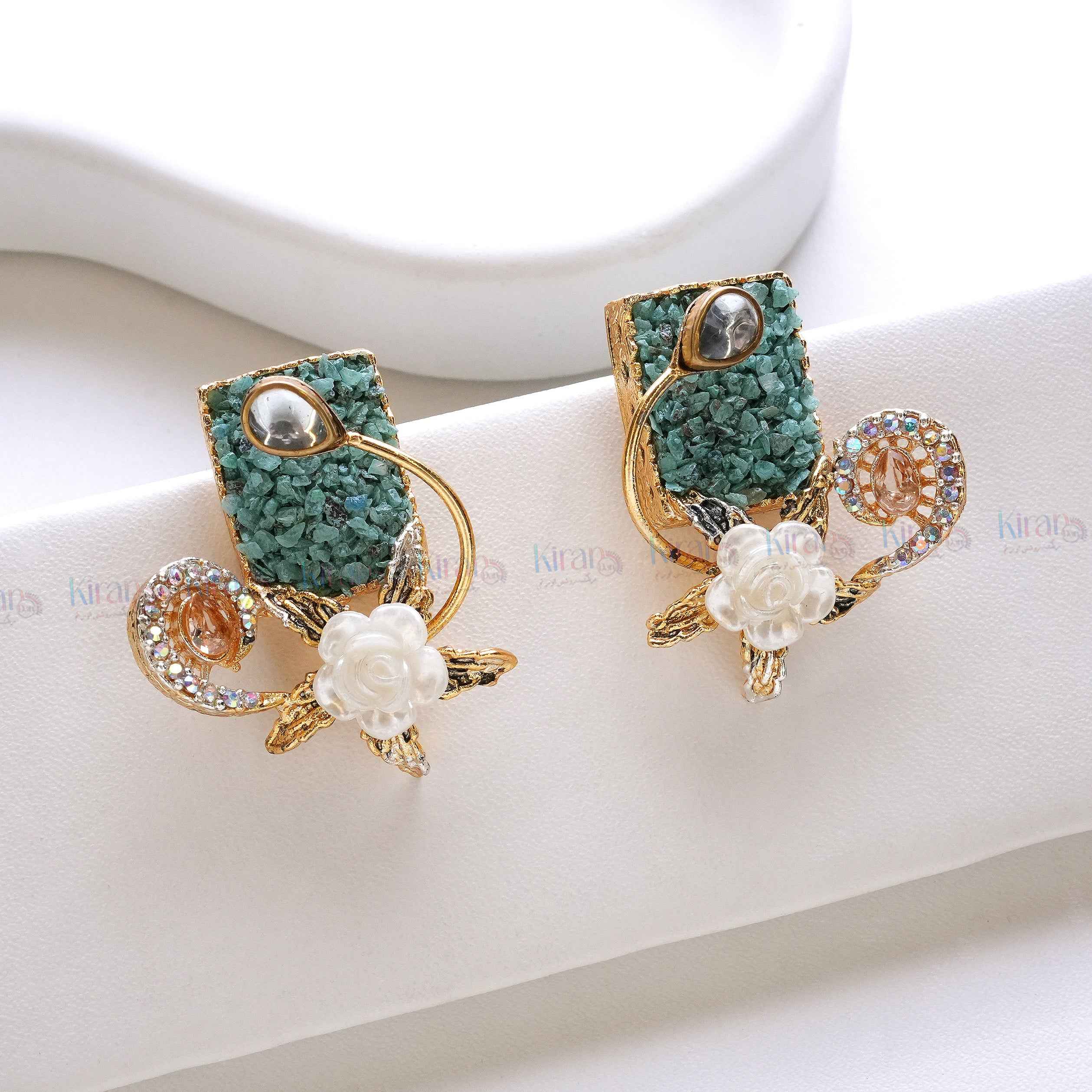 Pair of decorative earrings with green and gold design on a white surface