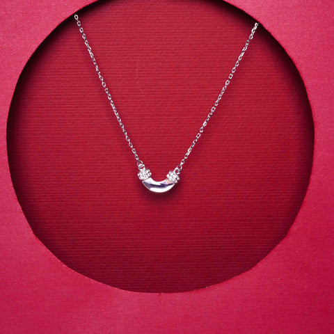 Silver necklace with a crescent moon pendant on a red background